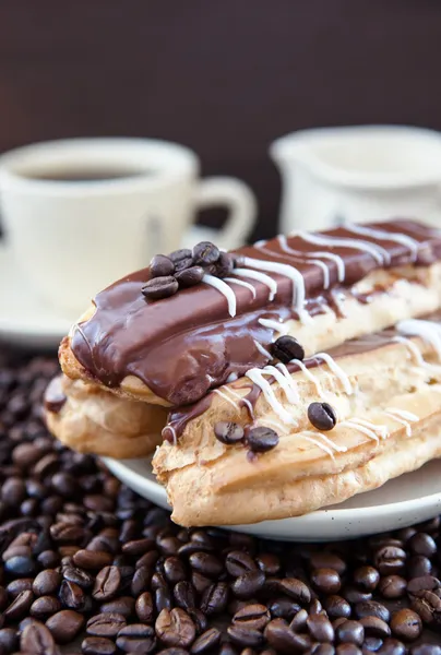 Chocolate eclairs on plate with coffee beans around — Stock Photo, Image