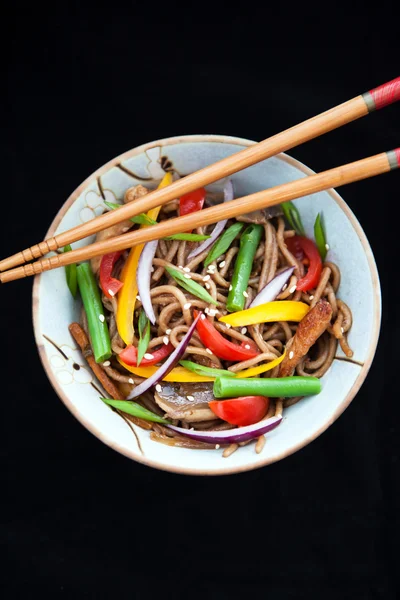 Buckwheat noodles with chicken and vegetables on black — Stock Photo, Image