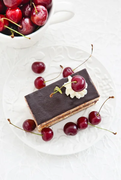 Porção de bolo de ópera decorado com cereja fresca — Fotografia de Stock