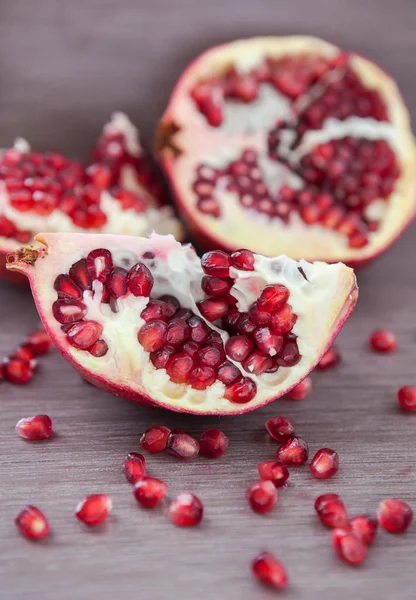 Pomegranate and pomegranate seeds on a wooden board — Stock Photo, Image