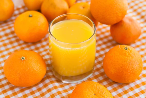 Copo de suco de laranja com algumas tangerinas — Fotografia de Stock