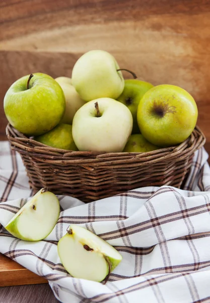Свежие яблоки в корзине на деревянном столе — стоковое фото