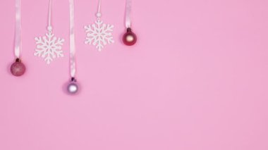 Pastel Noel süslemeleri. Toplar ve kar taneleri. Kurdeleye asılmış bir şekilde belirip kayboluyorlar. Hareketi durdur
