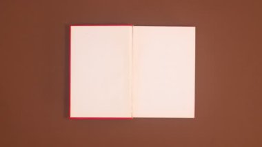 Kahverengi temalı kırmızı bir kitap görünür ve açılır. Hareketi durdur