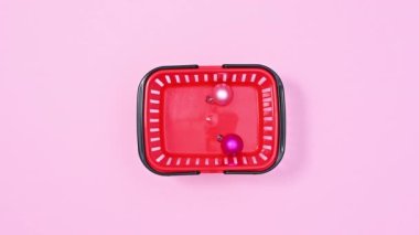 Pastel pembe temalı Noel süsleriyle dolu alışveriş sepeti. Hareketi durdur