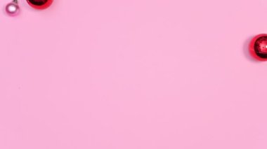 Kırmızı ve pembe Noel balolarının minimum Noel düzenlemesi pastel pembe temada görünür. Hareketi durdur