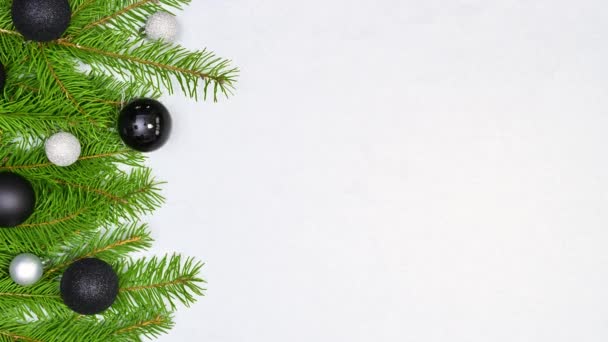 停止用黑色和银色装饰装饰在白色主题左边的松树枝制作圣诞花环的动作动画 — 图库视频影像