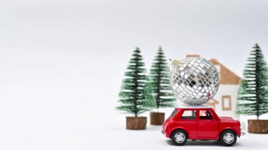 Noel sahnesinde çatıda parlak bir Noel topu süren klasik kırmızı bir araba. Hareketi durdur