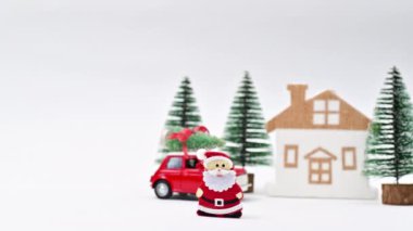 Noel ağaçları, klasik kırmızı araba ve evin önünde Santa Clouse olan bir Noel sahnesi. Hareketi durdur