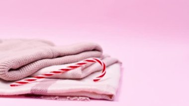 Pastel pembe arka plan. Kış eşarbı, kep ve Noel şekerli küçük Noel süsleri. Hareketi durdur