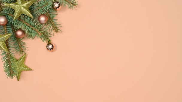 圣诞冷杉的枝条装饰着金色的圣诞装饰品和闪烁的灯光 呈现在橙色的主题上 停止运动 — 图库视频影像