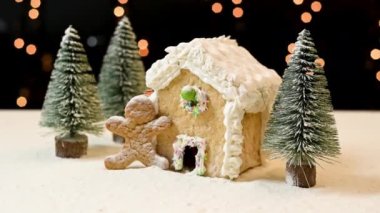 Noel için zencefilli kurabiye evi ve masada Noel ağaçları olan bir adam.