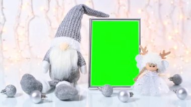 Yeşil ekran Noel çerçevesi Noel cücesi, melek ve masada küçük gümüş süslemelerle çevrili.