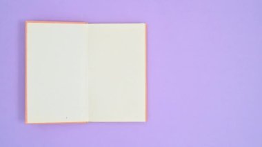 Portakal rengi ciltli kitap mor temalı ve açık. Dur hareketi düz yatıyordu