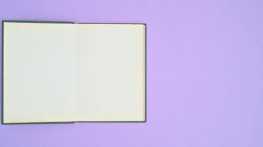 Mor temalı koyu yeşil kapaklı eski moda kitap ve kitap açılıyor. Dur hareketi düz yatıyordu