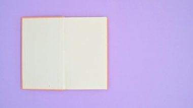 Portakal rengi ciltli kitap mor temalı ve açık. Dur hareketi düz yatıyordu