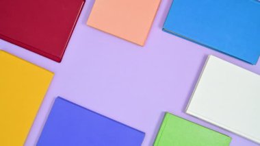 Farklı renkte sert kapaklı eski kitaplar mor temalı çerçeveler oluşturur. Hareketi durdur