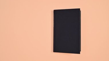 Siyah ciltli retro kitap turuncu temada iki taraftan dönüyor ve açılıyor. Dur hareketi düz yatıyordu