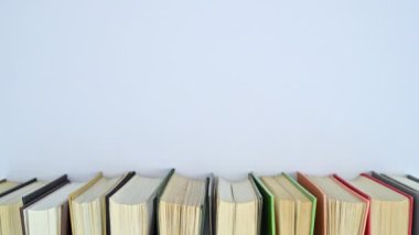 Farklı renklerde ciltli kitap yığını metin için boş alan ile kitaplıkta hareket eder. Dur hareketi düz yatıyordu