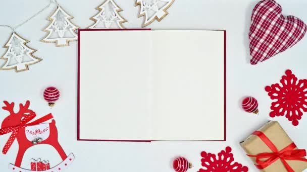 移动圣诞装饰和闪烁的灯周围打开的书的白色主题 停止运动平铺 — 图库视频影像