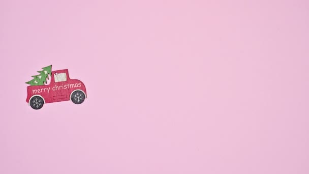 Mijając Mały Drewniany Czerwony Samochód Świąteczny Choinką Pastelowy Różowy Motyw — Wideo stockowe