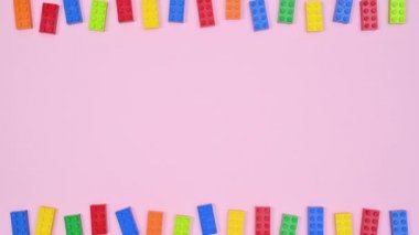 Çocukların renkli oyuncak tuğlaları pastel pembe temanın üstünde ve altında görünür. Hareketi durdur
