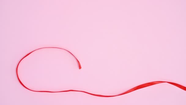 Red ribbon make Valentines day heart on pastel pink theme. Stop motion
