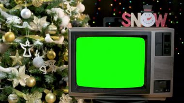 Güzel dekore edilmiş yılbaşı ağacının önünde yanıp sönen ışıklarla eski moda televizyon. 