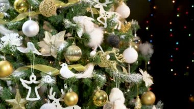 Altın, beyaz süsler ve yanıp sönen ışıklarla süslenmiş güzel bir Noel ağacı.