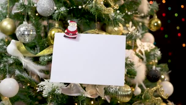 輝くライトとゴールドホワイト装飾クリスマスツリー上のサンタの飾りでフックグリーティングカードのための白い紙 — ストック動画