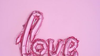 Pastel pembe temada Sevgililer Günü balonu görünüyor. Dur hareketi düz yatıyordu
