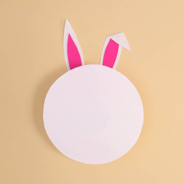 Pastel bej arka planda kağıt kart notlu Crative Paskalya tavşanı kulakları. Düz konsept