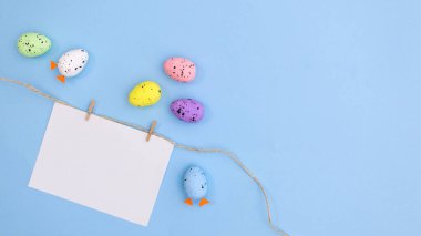 Paskalya için ipte renkli yumurtaların olduğu yaratıcı kağıt kart notu. Düz yatıyordu. Minimal bileşim. Bahar tatili kavramı