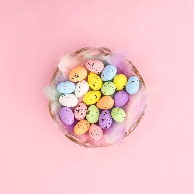 Tüylü ahşap sepet ve pastel parlak pembe arka planda renkli Paskalya yumurtaları. Sabit mevsim bahar tatili konsepti