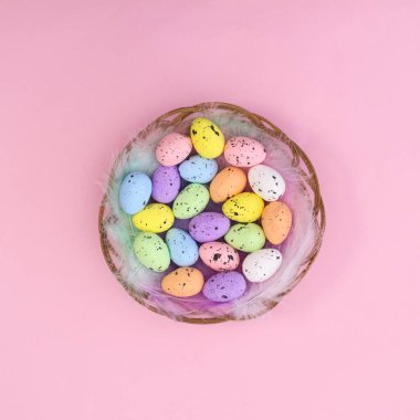 Tüylü ahşap sepetli ve pastel pembe temalı renkli yumurtalı mutlu Paskalya yaratıcı arka planı. Düz yatıyordu.