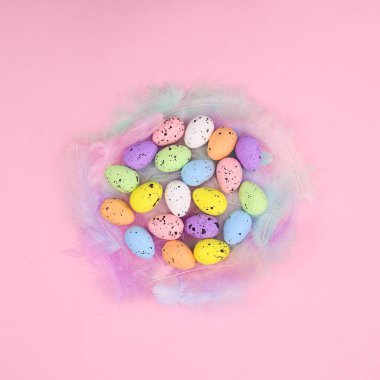 Parlak pembe arka planda renkli Paskalya yumurtaları olan zarif pastel tüyler. Minimum ilkbahar düzenlemesi vardı. Boşluğu kopyala