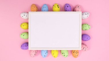 Kağıt kartın etrafındaki Paskalya yumurtaları pastel pembe arka plandaki uzay çerçevesini kopyalıyor. Dümdüz uzanıyordu. Yaratıcı kavram