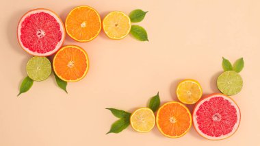 Fotokopi alanı, tropik yaz turunçgil meyveleri ve bej arka planda yeşil doğal yaprakları olan yaratıcı bir düzen. Düz yatıyordu