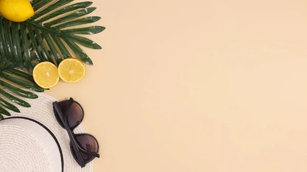Palmiye yaprakları, şapka, güneş gözlüğü ve organik limonlardan oluşan yaz plajı kompozisyonu. Tropik tatil konsepti yatıyordu. Boşluğu kopyala