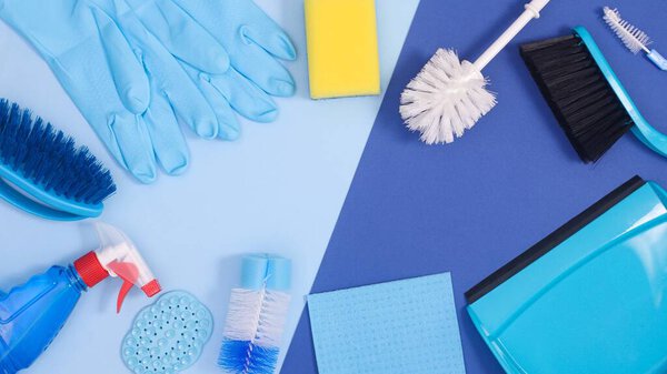 Creative copy space frame background with cleaning tools on pastel and deep blue theme. Flat lay