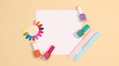 Manikür seti ve pastel bej arka planda tırnak cilası şişeleri olan yaratıcı bir fotokopi kağıdı. Düz yatıyordu