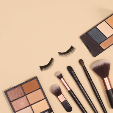 Pastel bej arka planda yaratıcı makyaj ve kozmetik ürünleri düzeni. Kopya alanı ile minimal bileşim yatıyordu