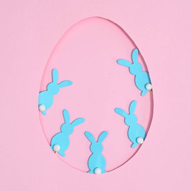 Pastel pembe arka planda mavi tavşanlı yumurta şekilli çerçeveler. Yaratıcı Paskalya konsepti