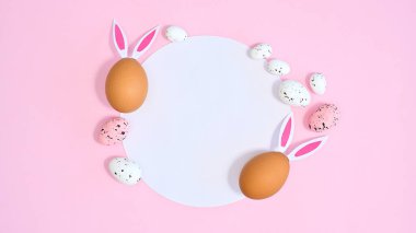 Pastel pembe arka planda Paskalya için tavşan kulaklı doğal yumurtalar. Düz yatay kopyalama alanı kağıt kartı kavramı
