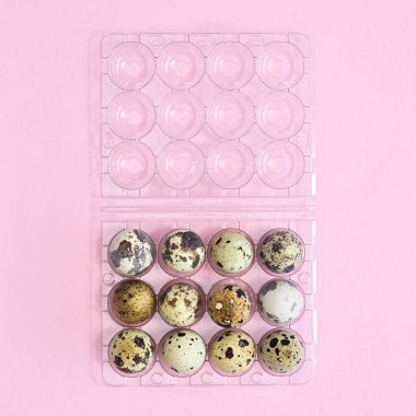 Plastik kutu ve bıldırcın doğal yumurtaları pastel pembe arka planda. Düz Paskalya konsepti