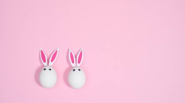 Pastel pembe arka planda tavşan kulaklı beyaz yumurtalar. Düz konsept çok az yaratıcıydı. Paskalya tatili