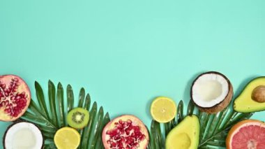 Summer tropical cyan background with palm leaves and exotic fruits. Copy space stop motion. Flat lay