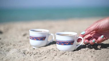 Kumsalda kahve içen bir kadın eli. Ağır çekimde kapat.