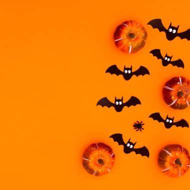 Autumn pumpkins and scary bats on orange background for Halloween holidays. Copy space. Flat lay