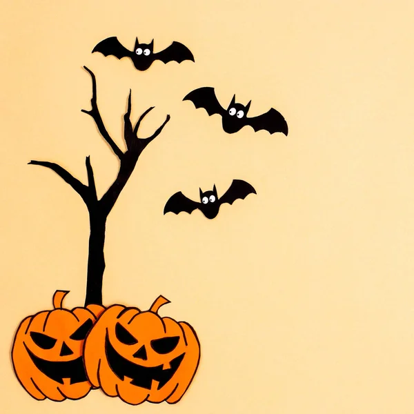 Halloween pumpkins with tree and bats on beige background. Creative copy space. Autumn holidays